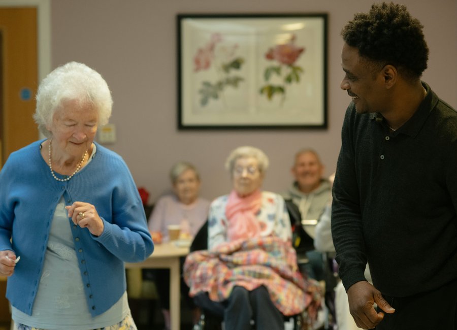 Elderly resident dancing joyfully with a member of the Rosewood team